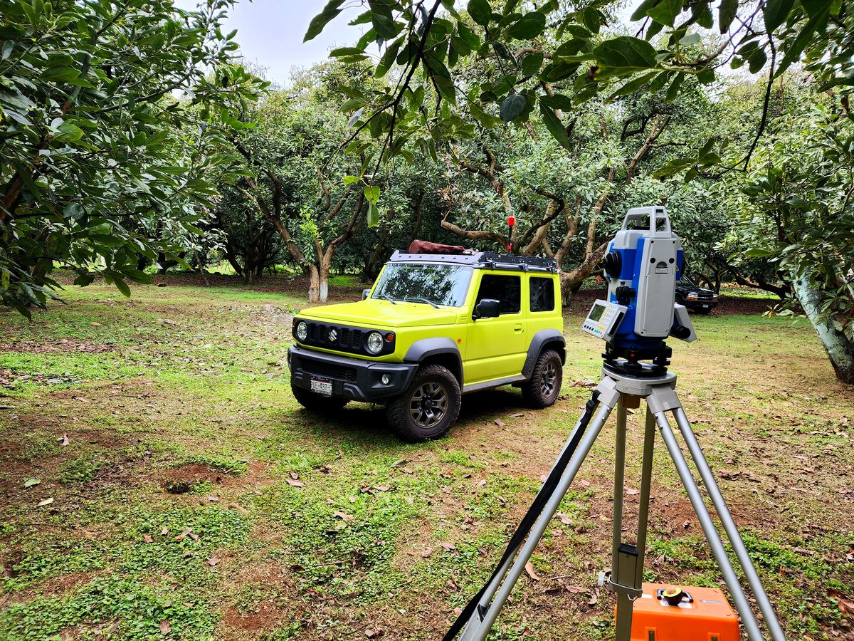 Estación total y vehículo de trabajo en huerta de aguacate